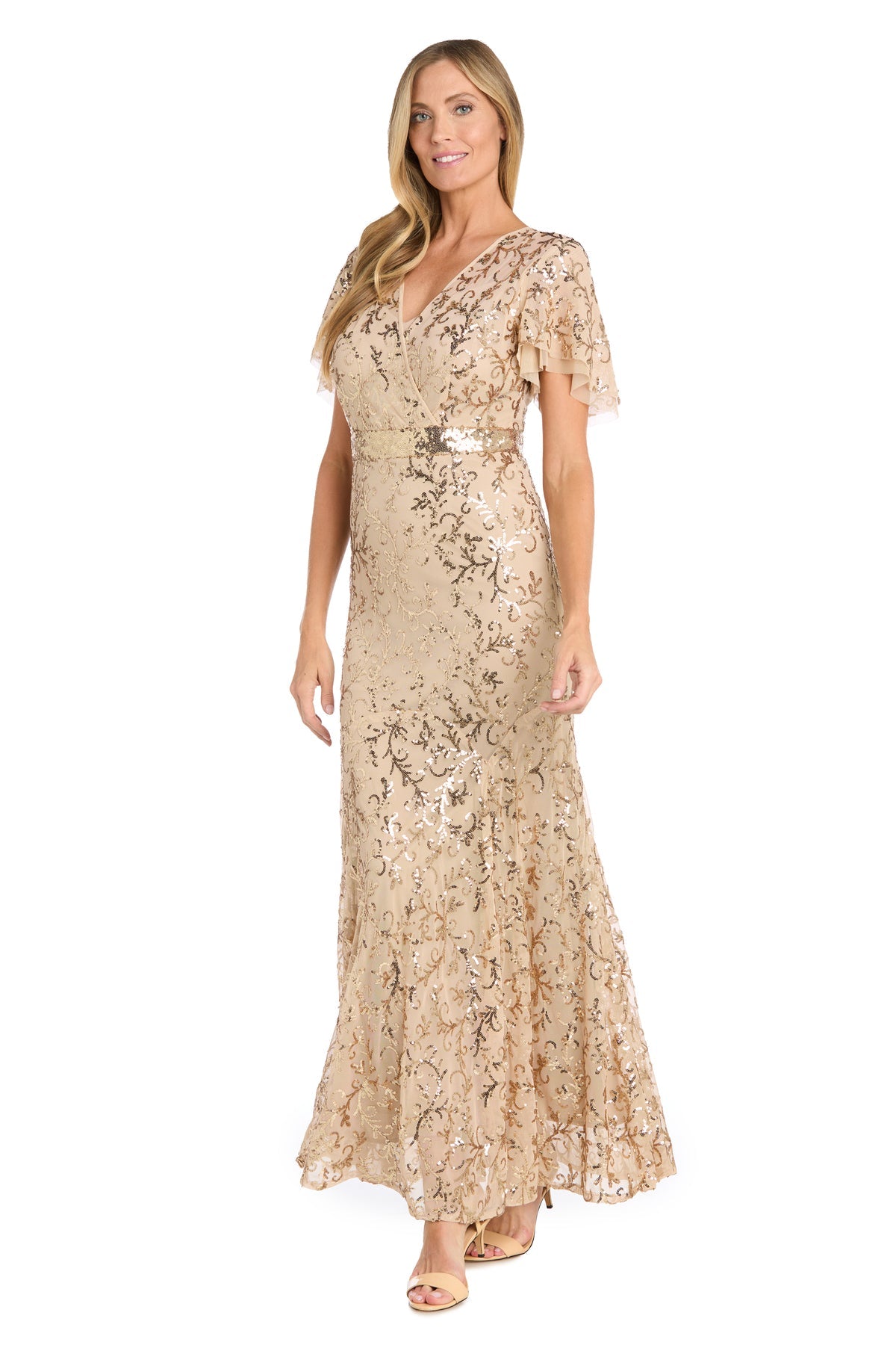 A woman wearing the R&M Richards 3425 Long Gold Sequin Formal Dress with short flutter sleeves and a V-neckline stands and smiles.